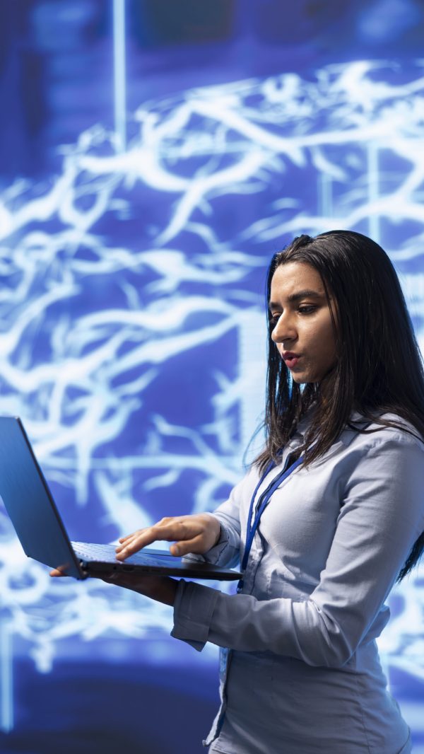 Software engineer solving tasks on laptop, running artificial intelligence programming scripts. Woman in modern lab using notebook to write lines of code for AI applications development